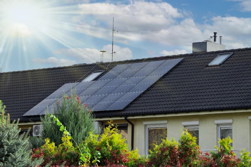 Panneaux solaires photovoltaïques installés sur toiture en tuiles d'une maison individuelle, sous un ciel ensoleillé.